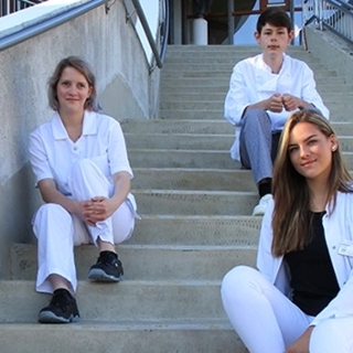 Mehrere Auzubildende sitzen lächelnd auf einer Treppe Mehrere Auzubildende sitzen lächelnd auf einer Treppe