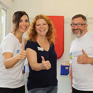 Zwei Frauen und ein Mann lachen in die Kamera und halten die Daumen hoch Zwei Frauen und ein Mann lachen in die Kamera und halten die Daumen hoch