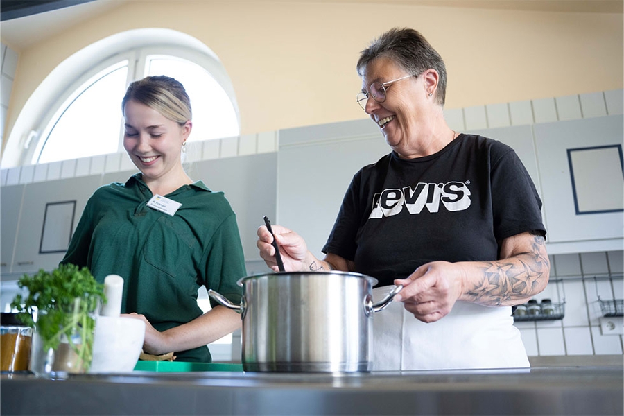 Zwei Personen stehen am Herd und kochen gemeinsam eine Mahlzeit