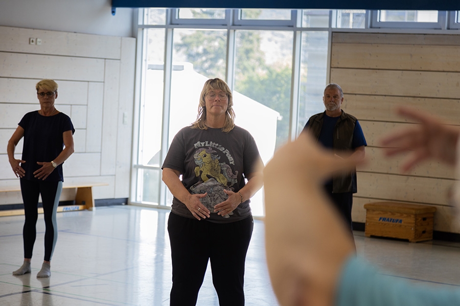 Zwei Patient*innen in der Sporthalle beim Durchführen vom Qigong-Übungen Zwei Patient*innen in der Sporthalle beim Durchführen vom Qigong-Übungen